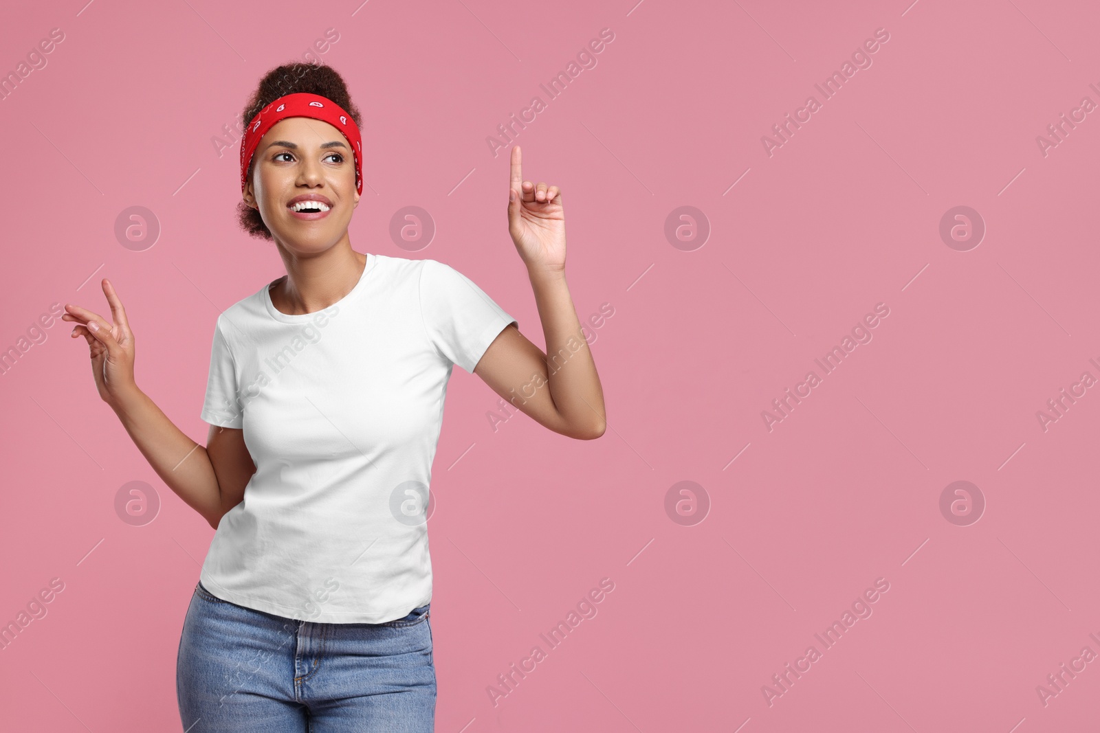 Photo of Happy young woman in stylish headband dancing on pink background. Space for text