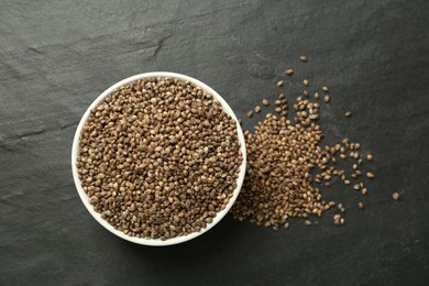 Photo of Ceramic bowl with chia seeds on black table, flat lay. Cooking utensil