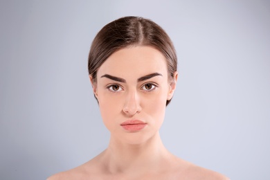 Beautiful woman with perfect eyebrows on light background