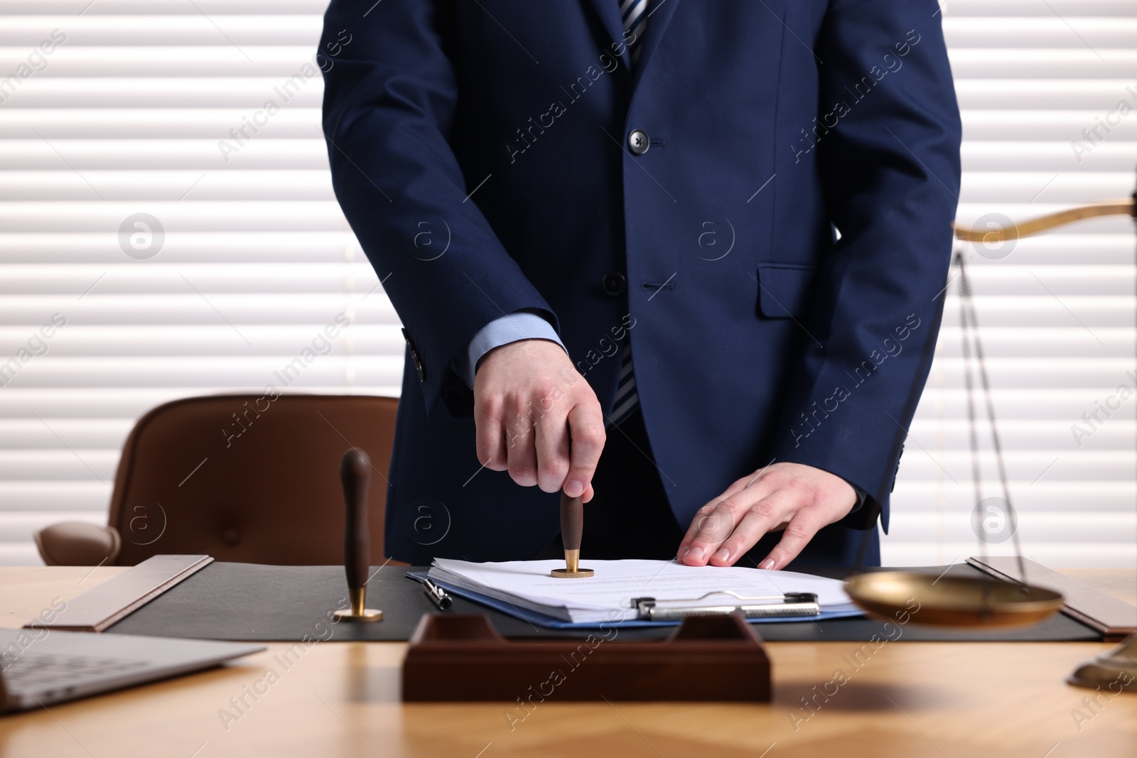 Photo of Notary stamping document at table in office, closeup