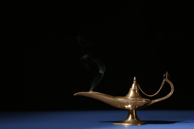 Aladdin lamp of wishes on table against black background