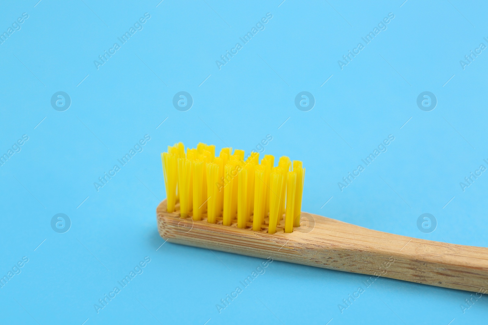 Photo of Toothbrush made of bamboo on light blue background, closeup