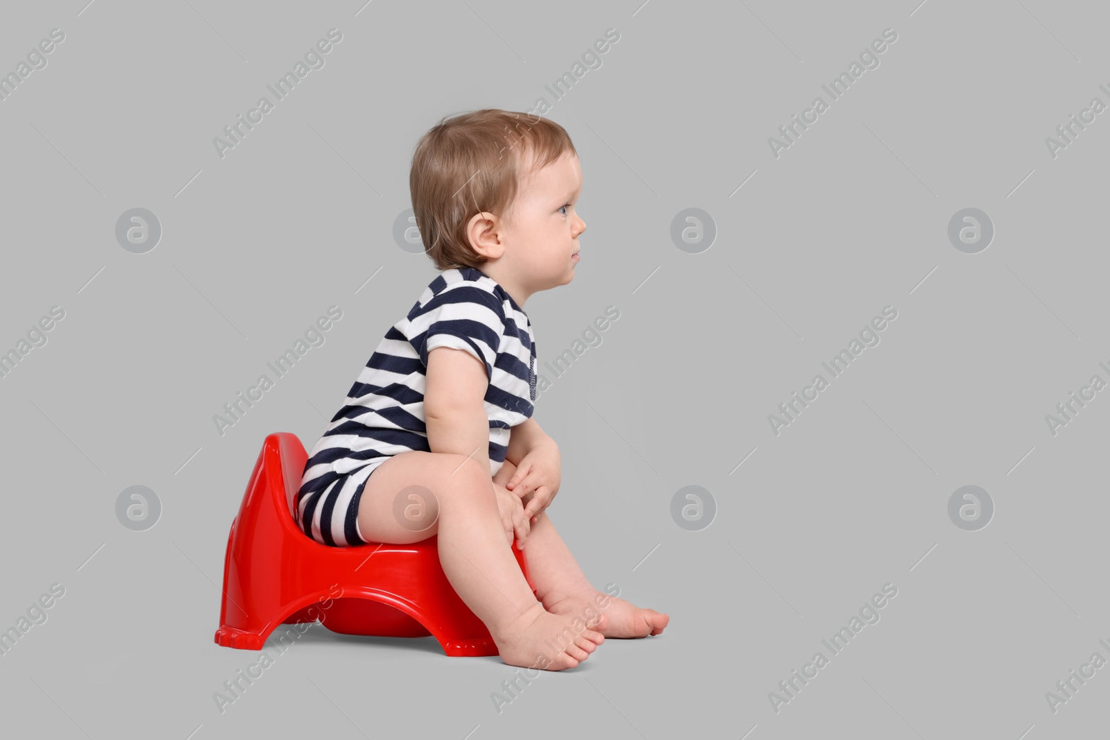 Photo of Little child sitting on baby potty against light grey background, space for text