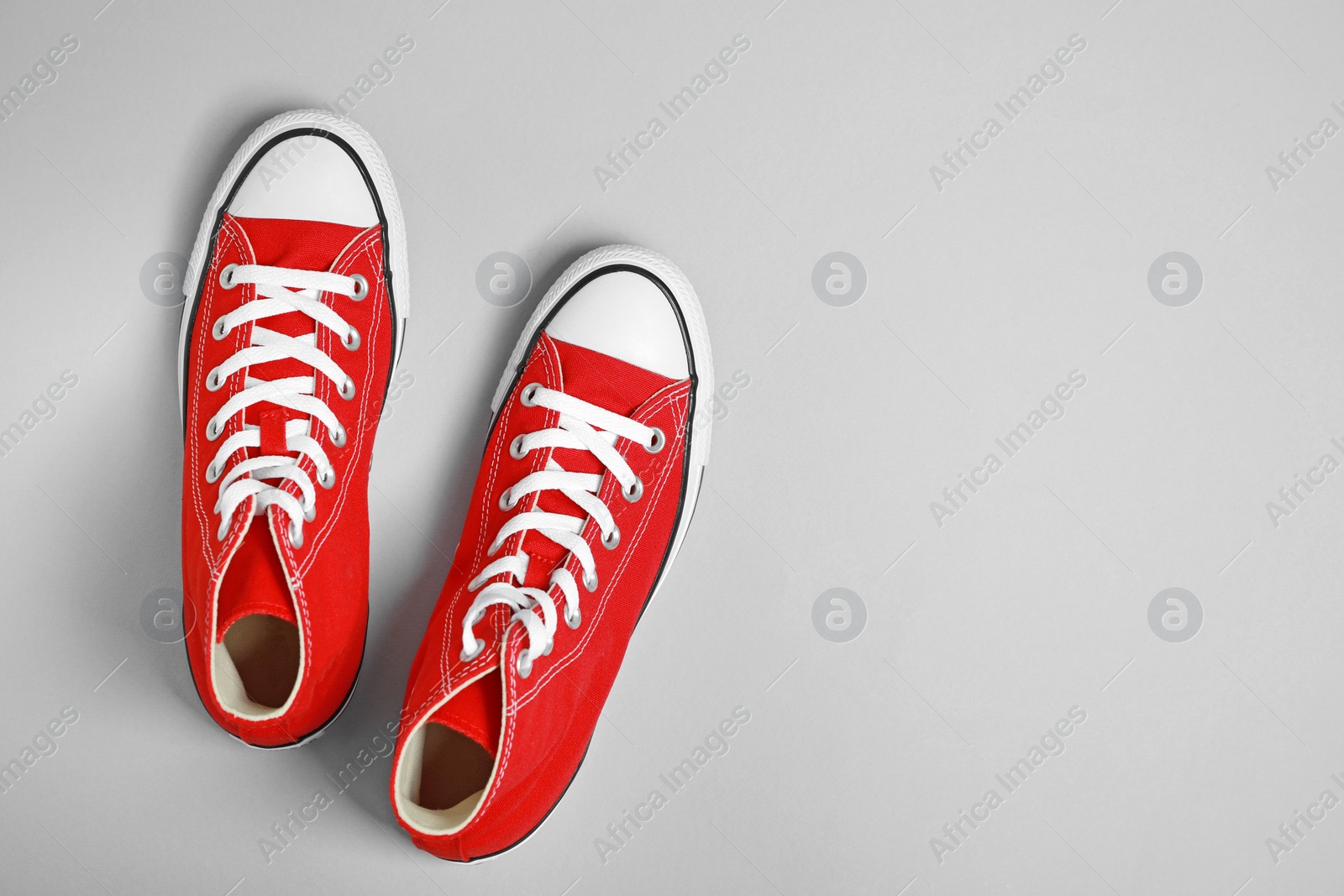 Photo of Pair of new stylish red sneakers on light grey background, flat lay. Space for text