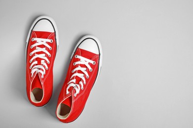 Pair of new stylish red sneakers on light grey background, flat lay. Space for text