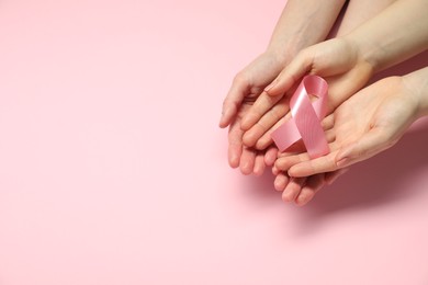 Photo of Breast cancer awareness. Women holding pink ribbon on color background, top view. Space for text