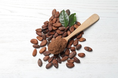 Flat lay composition with cocoa beans and powder on white wooden table