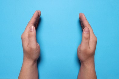 Woman holding on light blue background, closeup of hands. Space for text