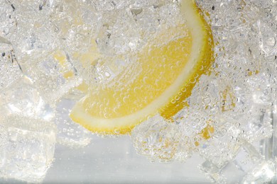 Photo of Juicy lemon slice and ice cubes in soda water on white background, closeup