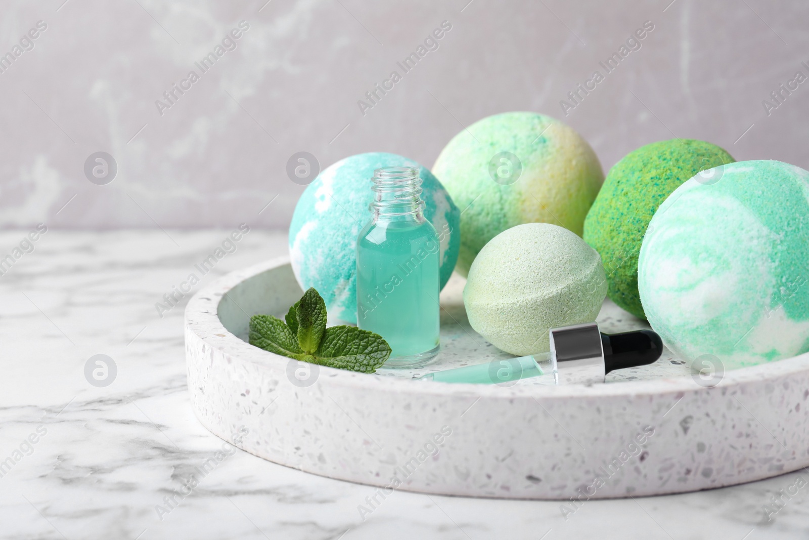 Photo of Fragrant bath bombs, oil and mint on white marble table