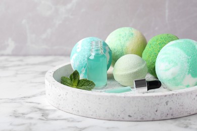 Photo of Fragrant bath bombs, oil and mint on white marble table