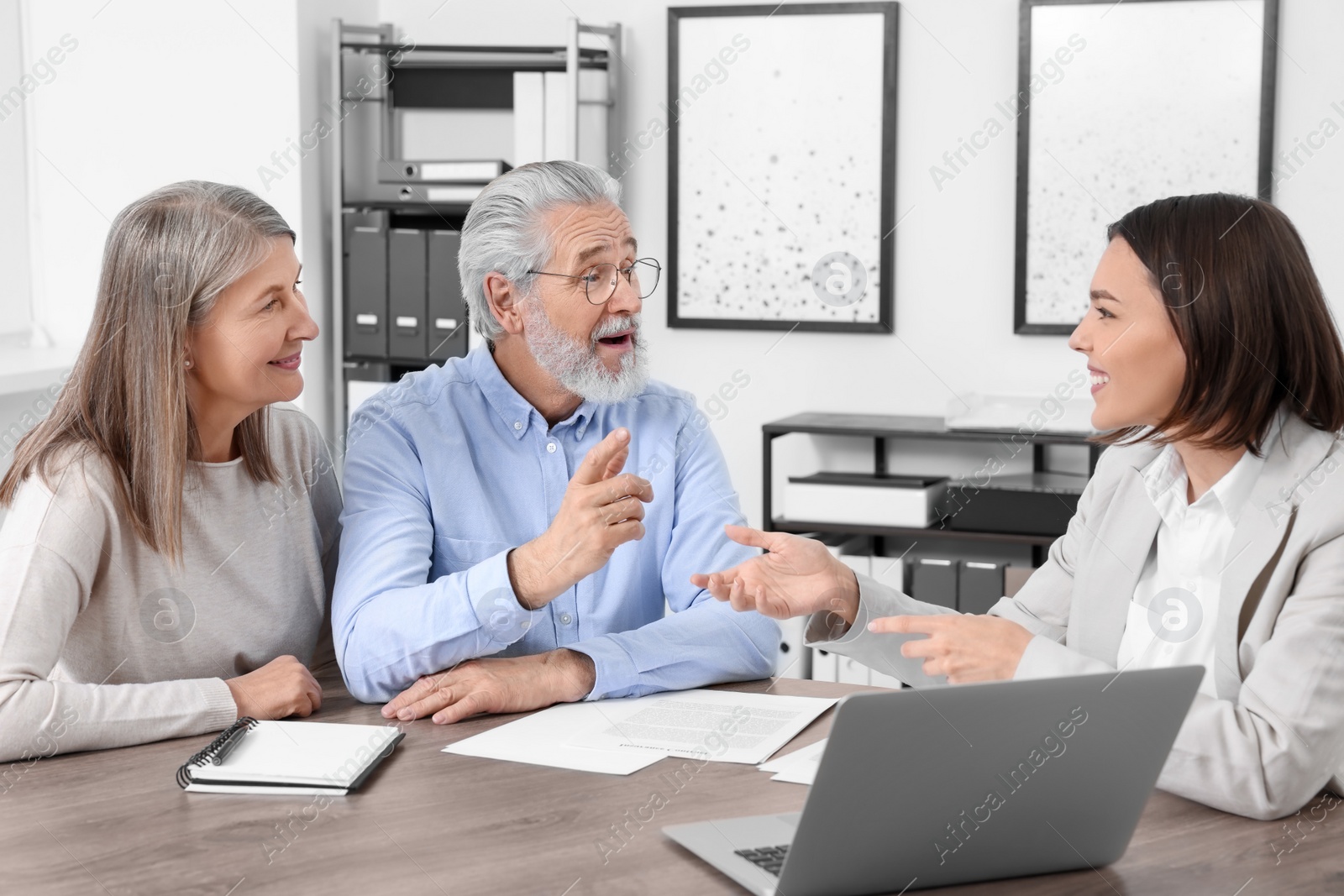 Photo of Elderly couple consulting insurance agent about pension plan at wooden table indoors