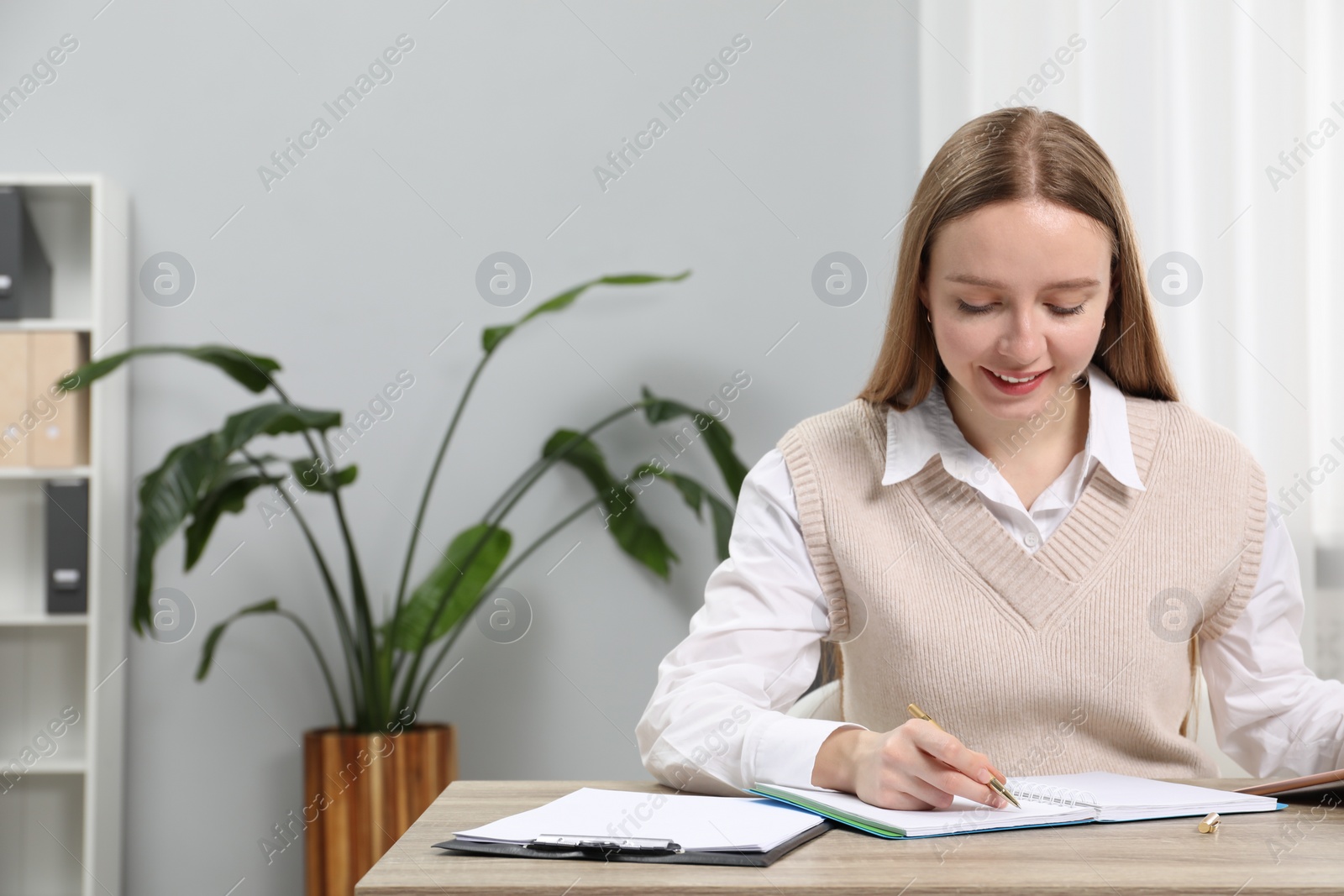 Photo of Woman taking notes at wooden table in office, space for text