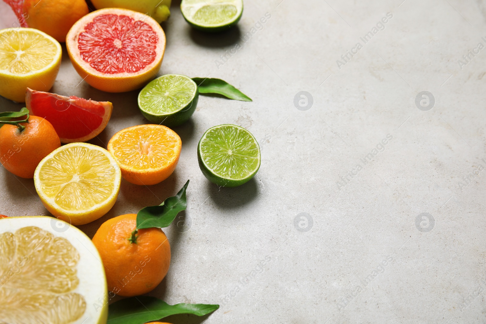 Photo of Different citrus fruits on grey background. Space for text