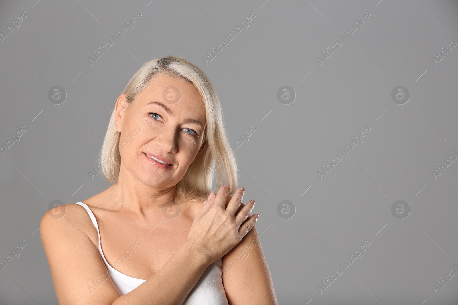 Photo of Portrait of beautiful mature woman on grey background. Space for text