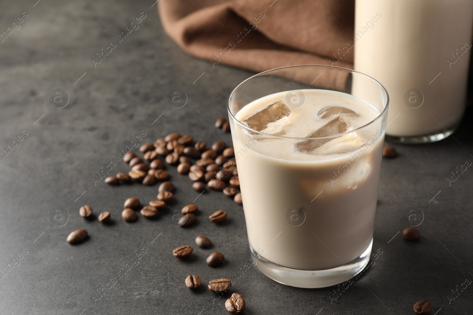 Photo of Coffee cream liqueur in glass and beans on grey table