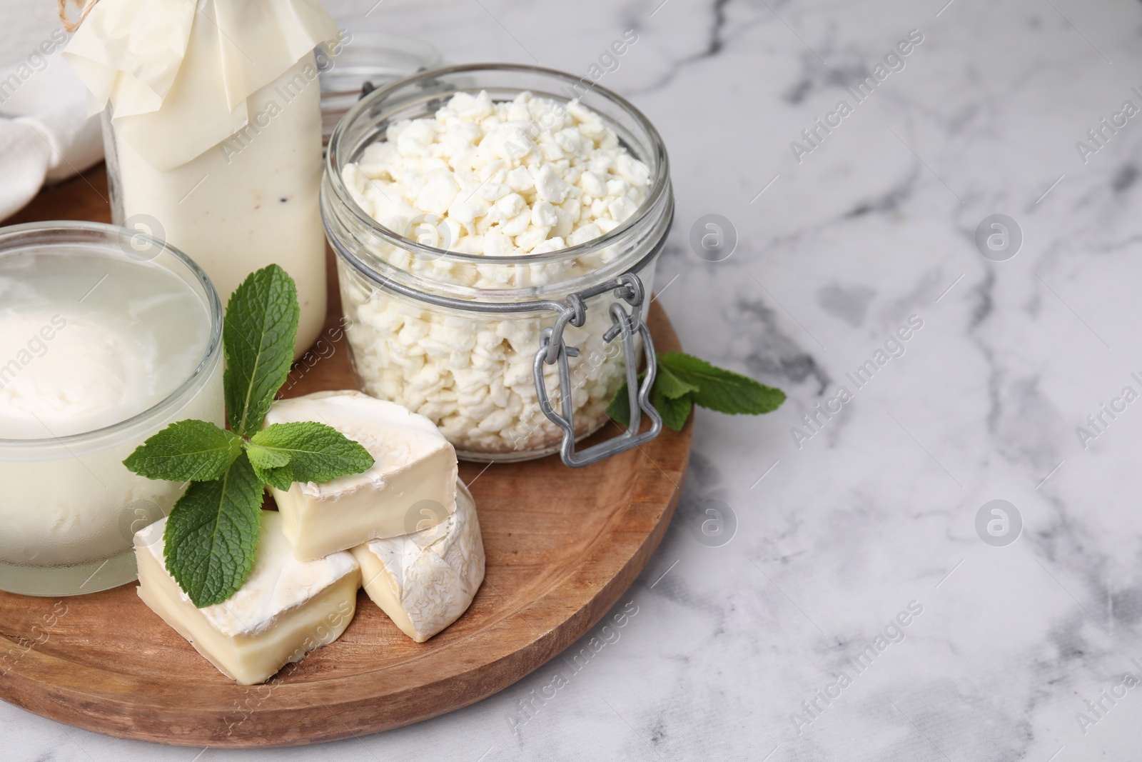 Photo of Different dairy products and mint on white marble table, space for text