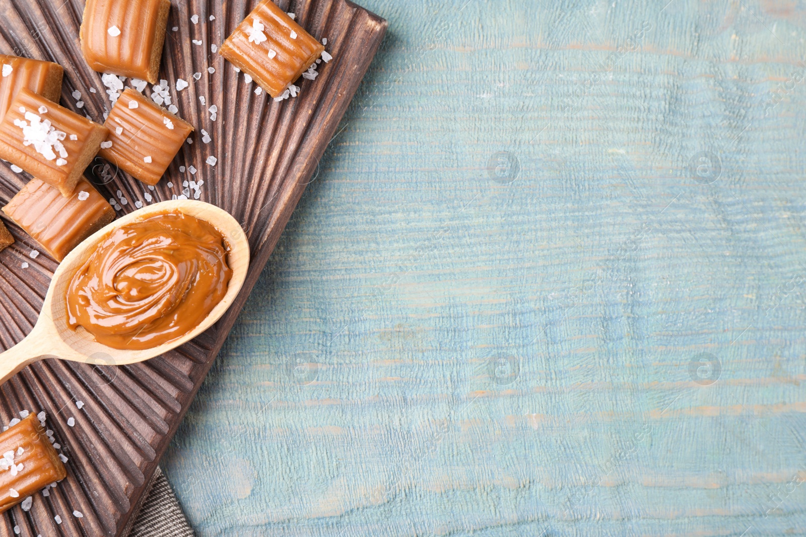 Photo of Salted caramel on blue wooden table, top view. Space for text