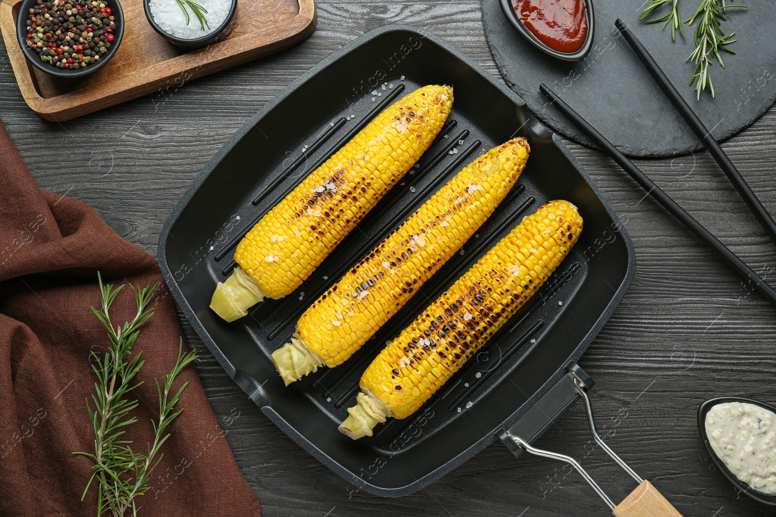 Photo of Flat lay composition with tasty grilled corn on dark grey wooden table