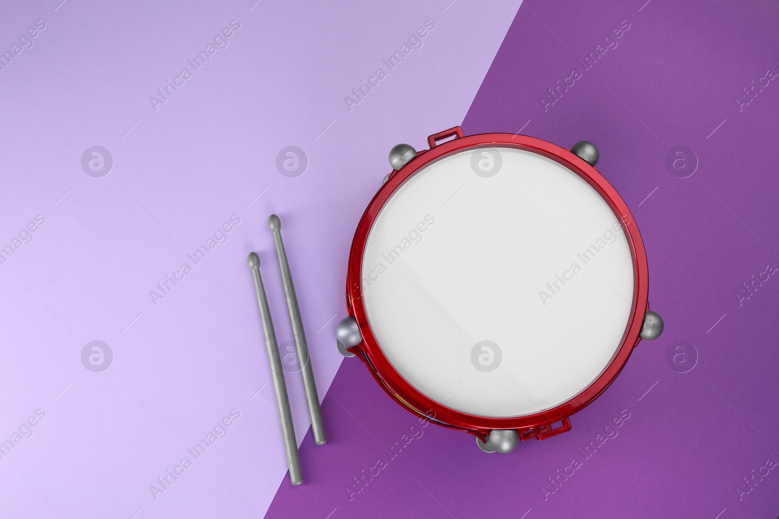 Photo of Children's drum with drumsticks on color background, top view. Space for text