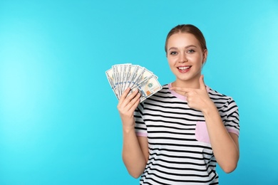 Portrait of happy young woman with money on color background. Space for text