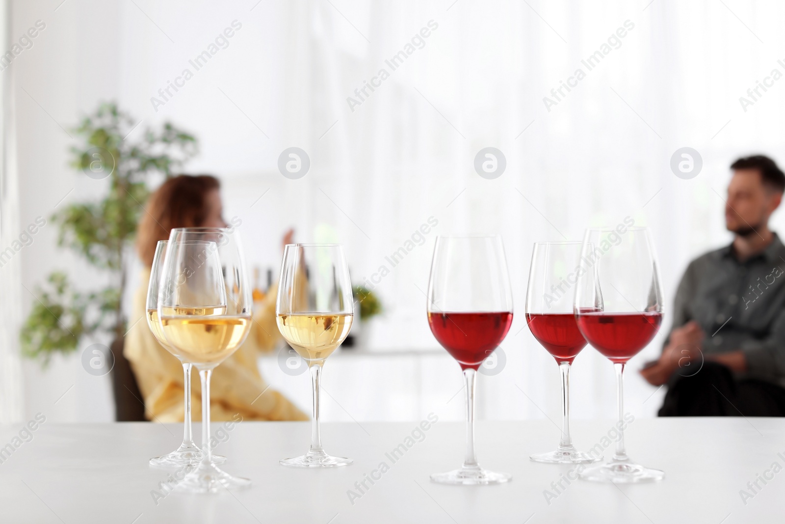 Photo of Glasses with delicious wine and blurred couple on background