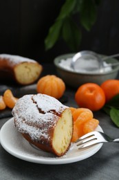 Photo of Piece of delicious homemade yogurt cake with powdered sugar and tangerines on gray table