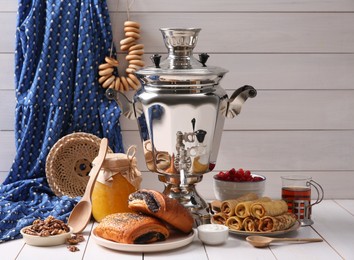 Photo of Traditional Russian samovar and treats on white wooden table