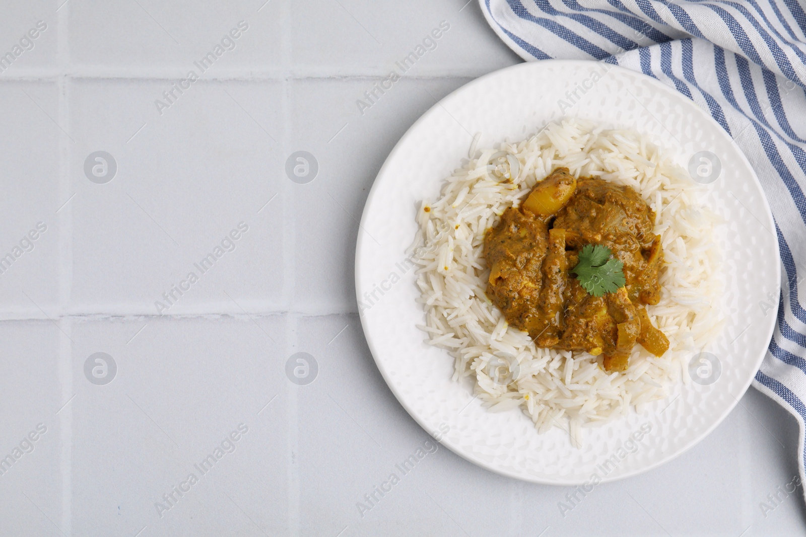 Photo of Delicious chicken curry with rice on white tiled table, top view. Space for text