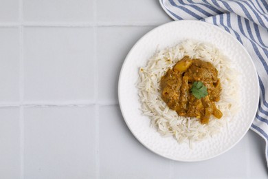 Photo of Delicious chicken curry with rice on white tiled table, top view. Space for text