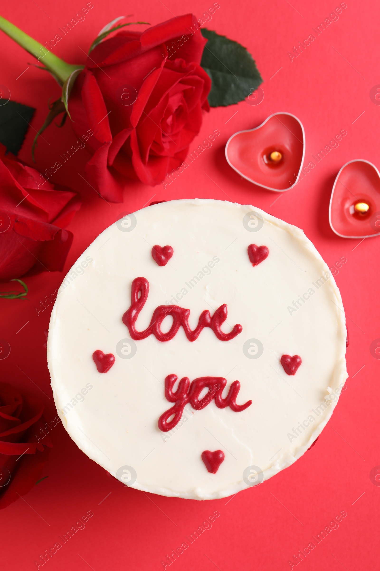 Photo of Bento cake with text Love You, roses and candles on red table, flat lay. St. Valentine's day surprise