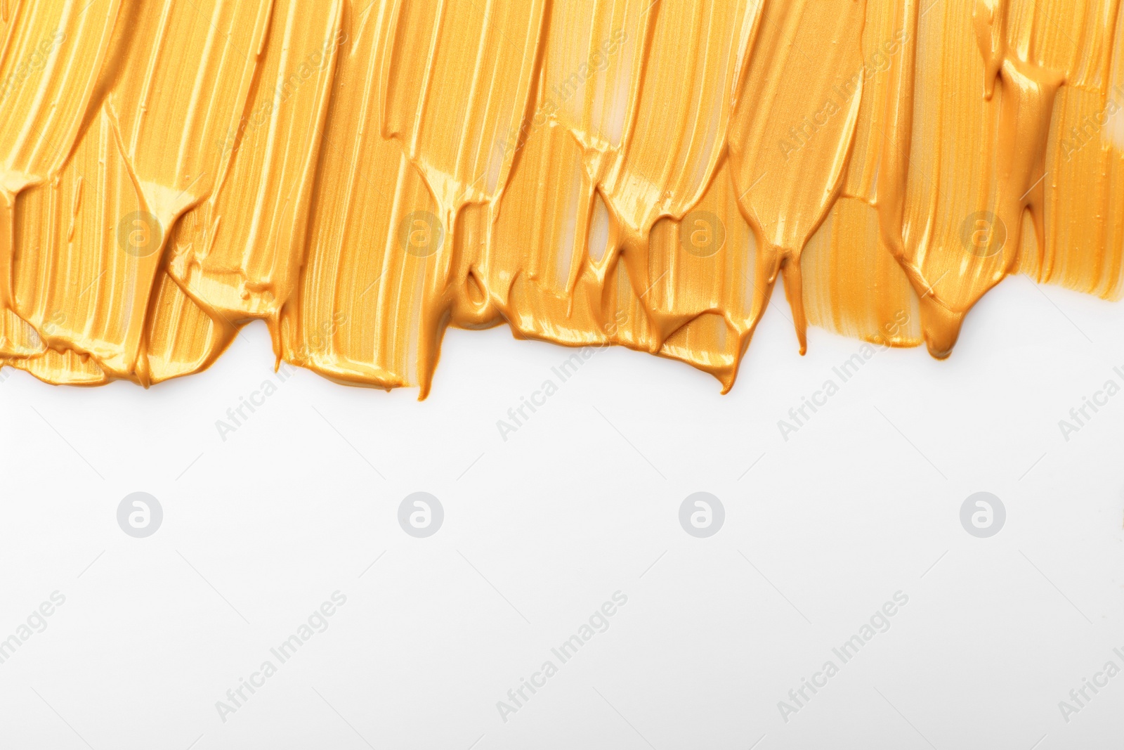 Photo of Strokes of gold paint isolated on white, top view