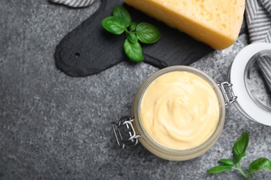 Photo of Tasty cheese sauce and basil on grey table, flat lay. Space for text