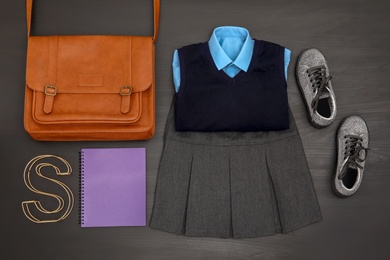 School uniform for girl and bag on wooden background, top view