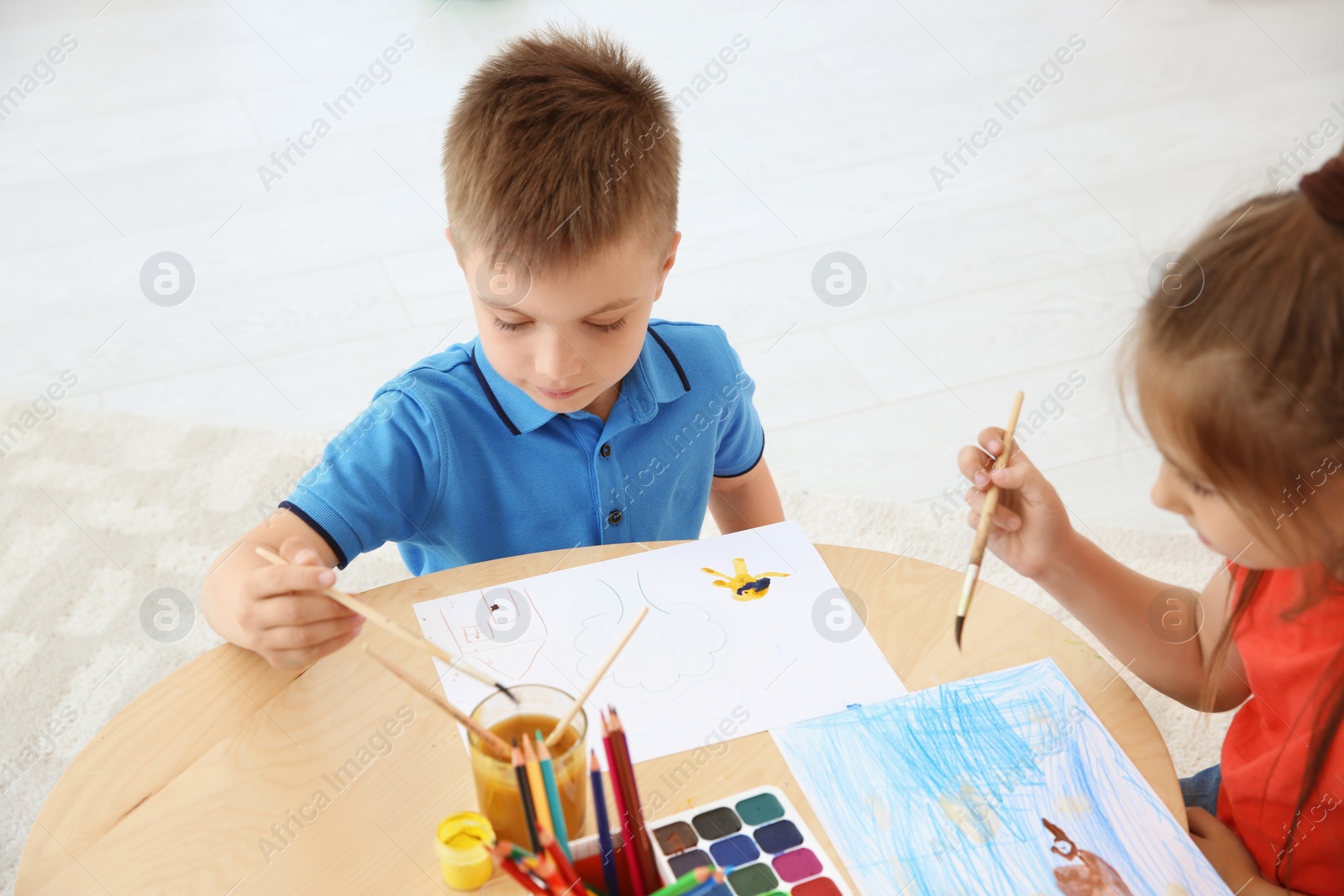 Photo of Cute little children painting at table in playing room