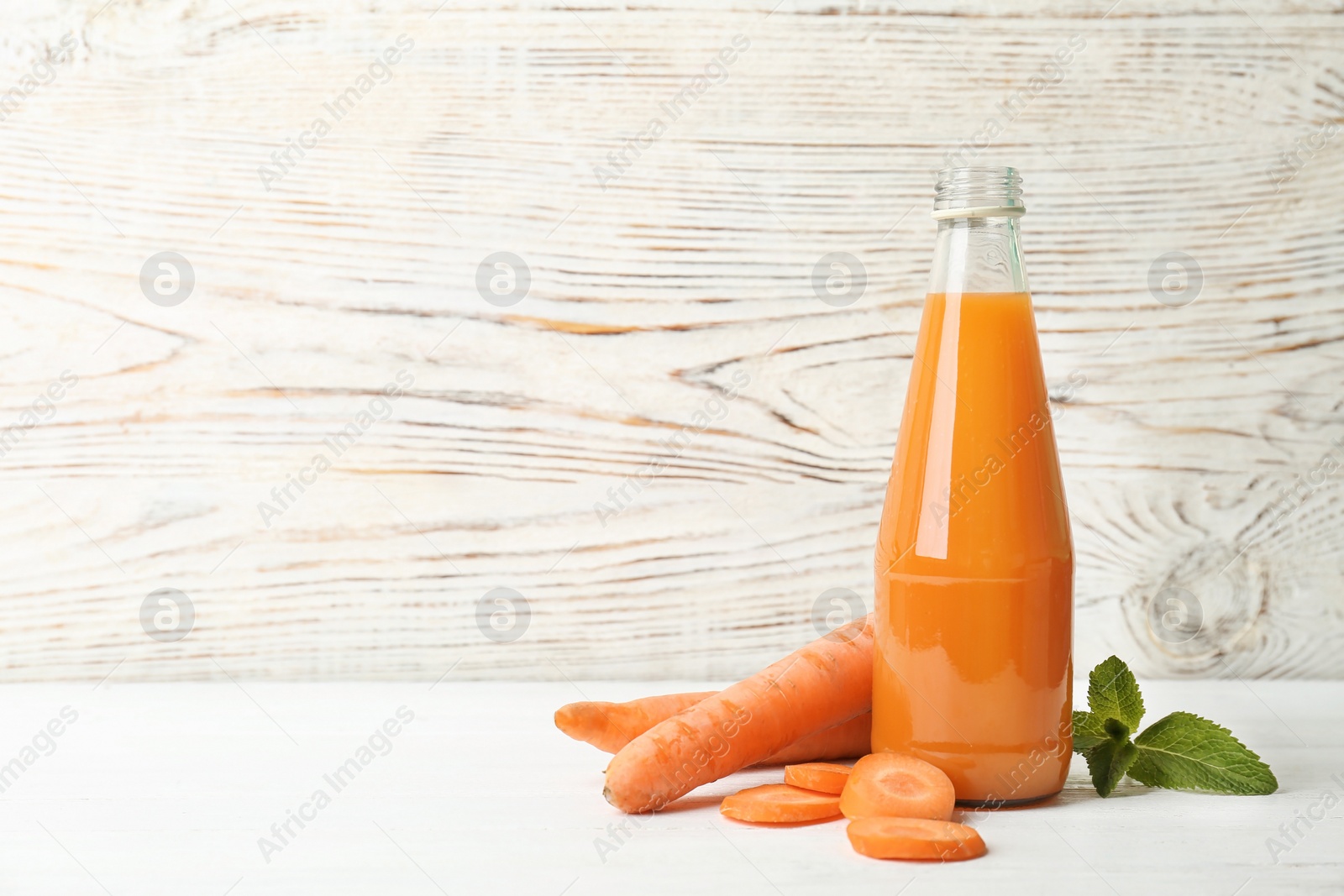 Photo of Bottle with tasty carrot juice on table