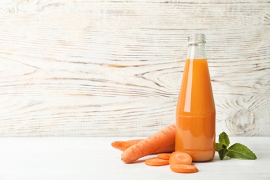 Photo of Bottle with tasty carrot juice on table