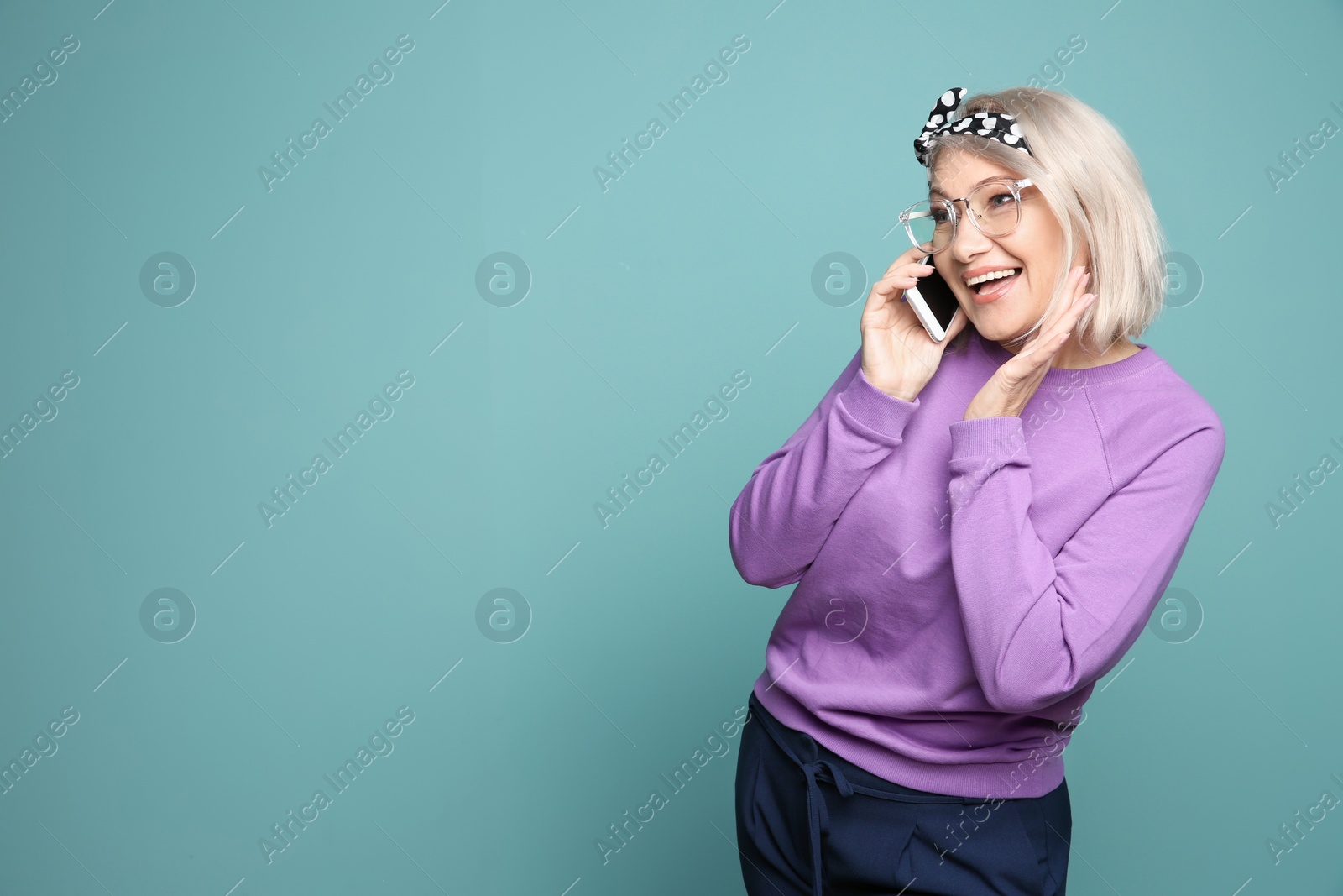 Photo of Mature woman talking on mobile phone against color background