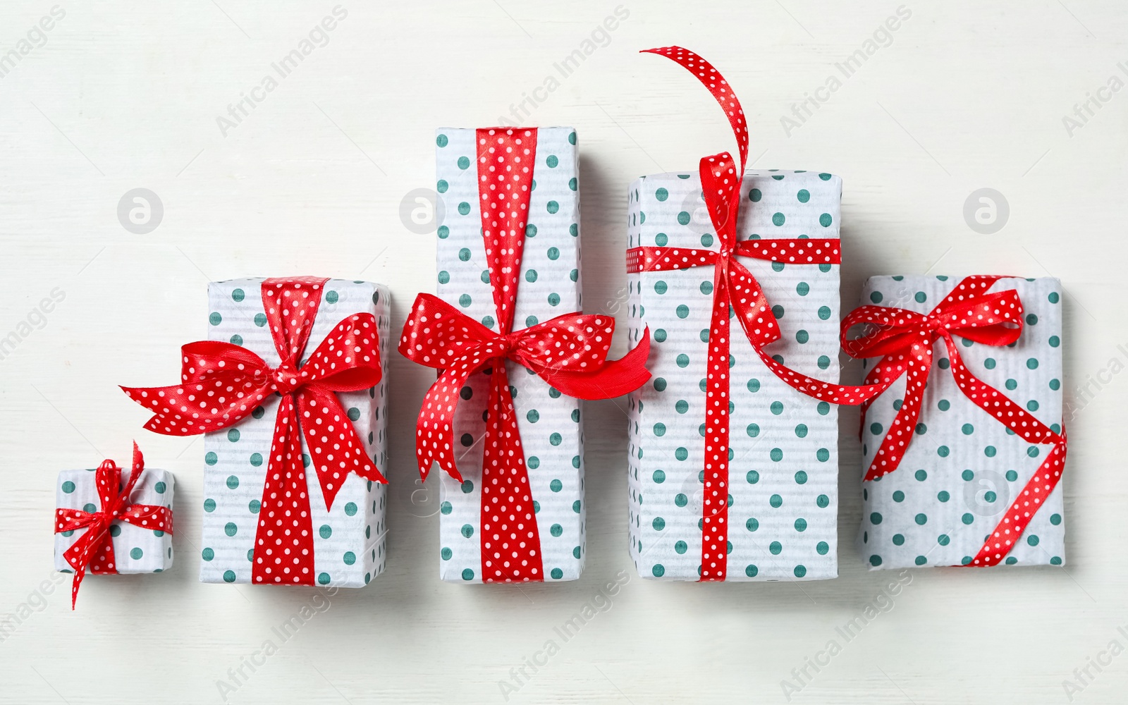 Photo of Christmas gift boxes with red bows on white wooden background, flat lay