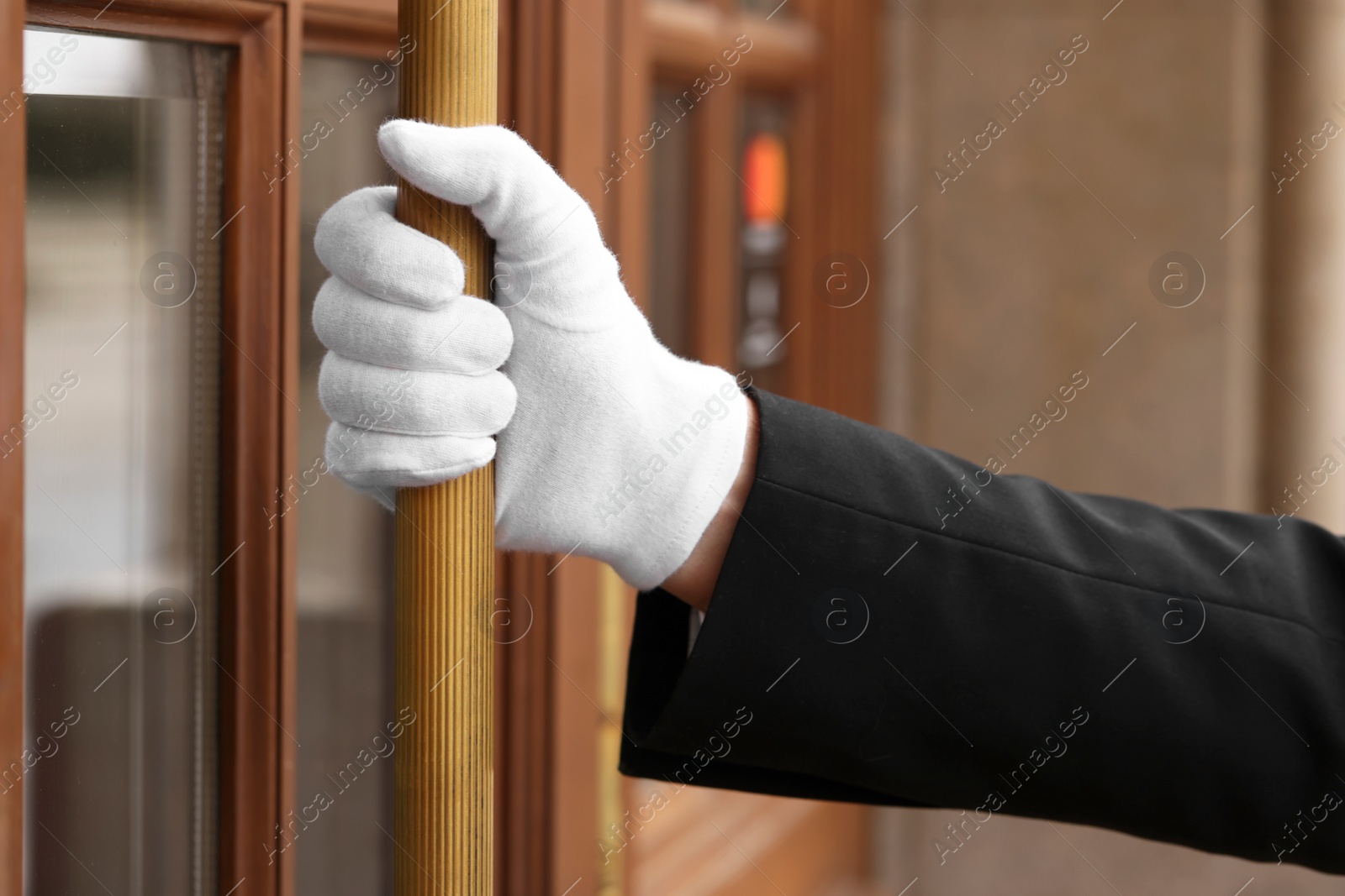 Photo of Butler in suit and white gloves opening hotel door, closeup