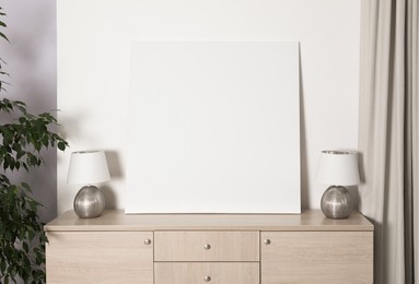 Photo of Blank canvas on wooden cabinet indoors. Space for design