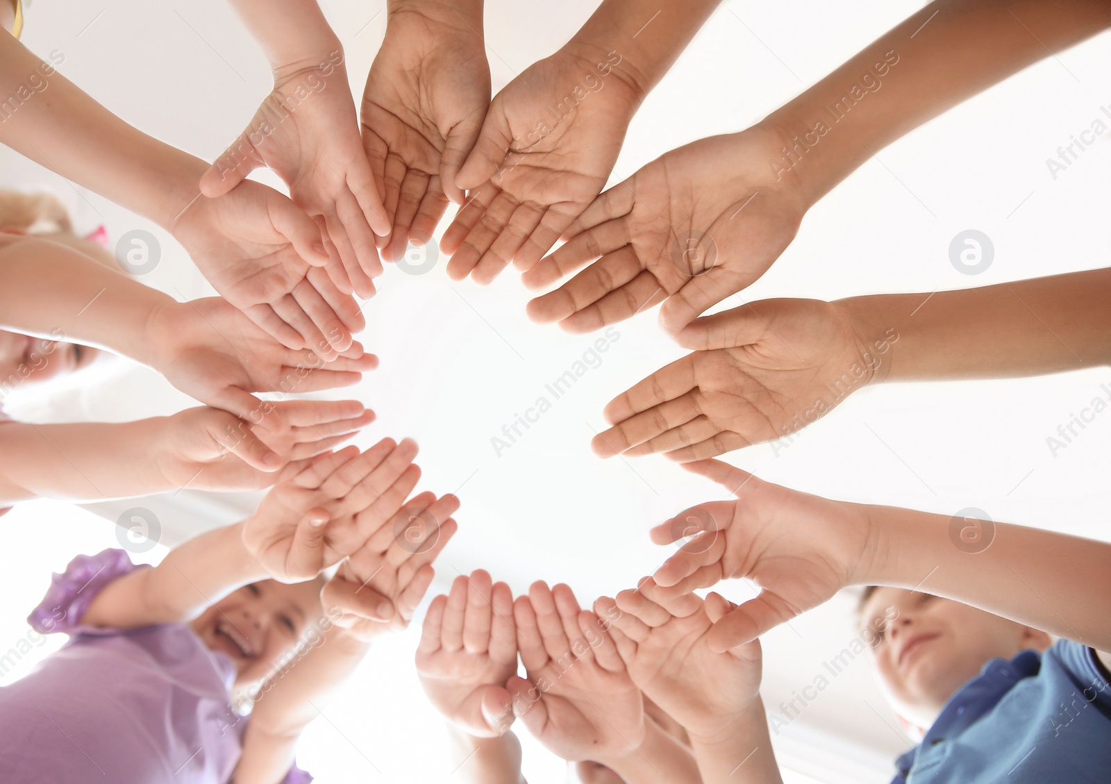 Photo of Little children putting their hands together indoors, view from below. Unity concept