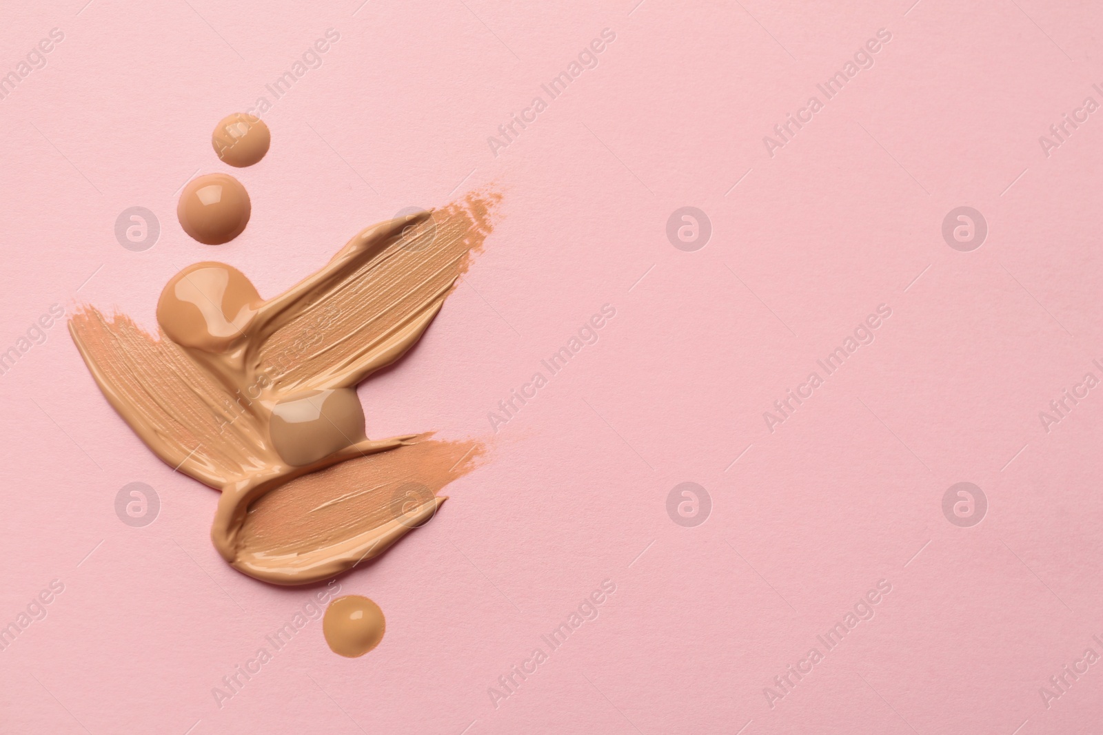 Photo of Samples of liquid skin foundation on pink background, top view. Space for text