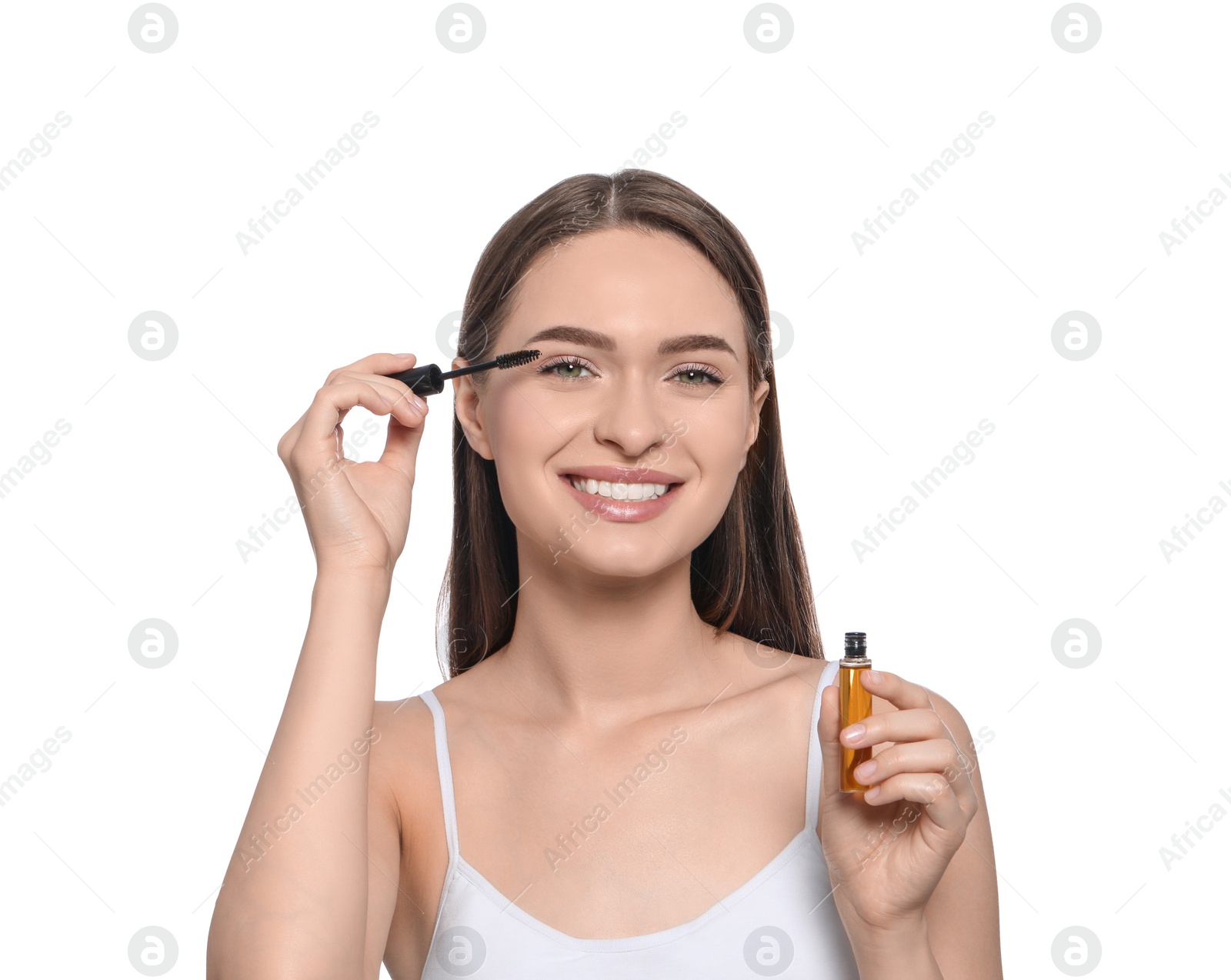 Photo of Young woman applying oil onto her eyelashes on white background