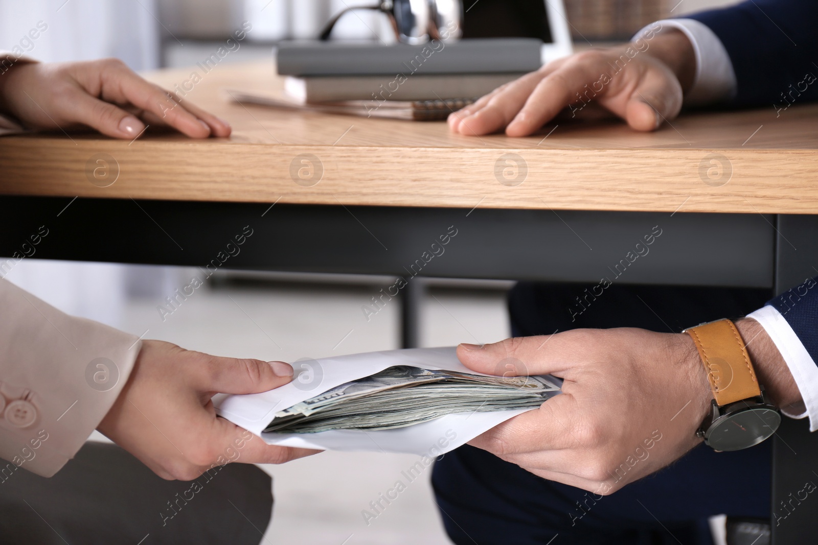 Photo of Woman giving bribe to man under table in office, closeup