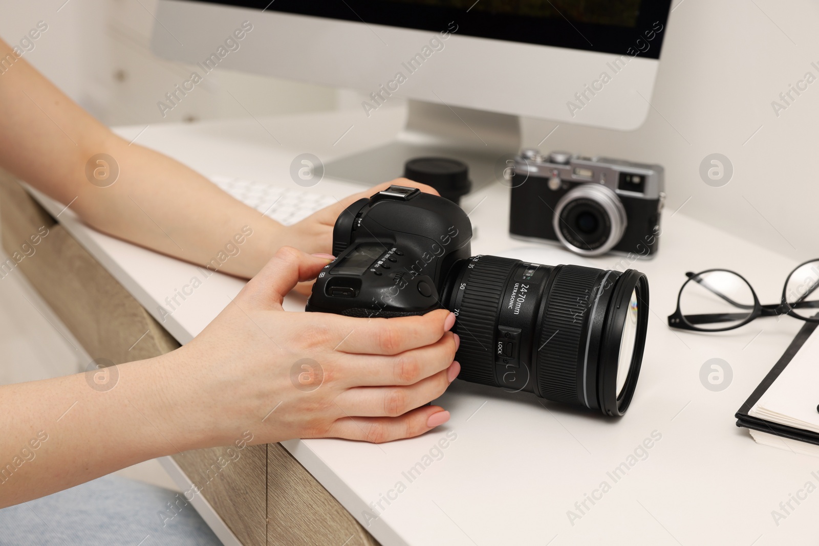 Photo of Photographer with camera at white table indoors, closeup