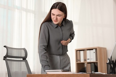 Photo of Woman having heart attack near table in office