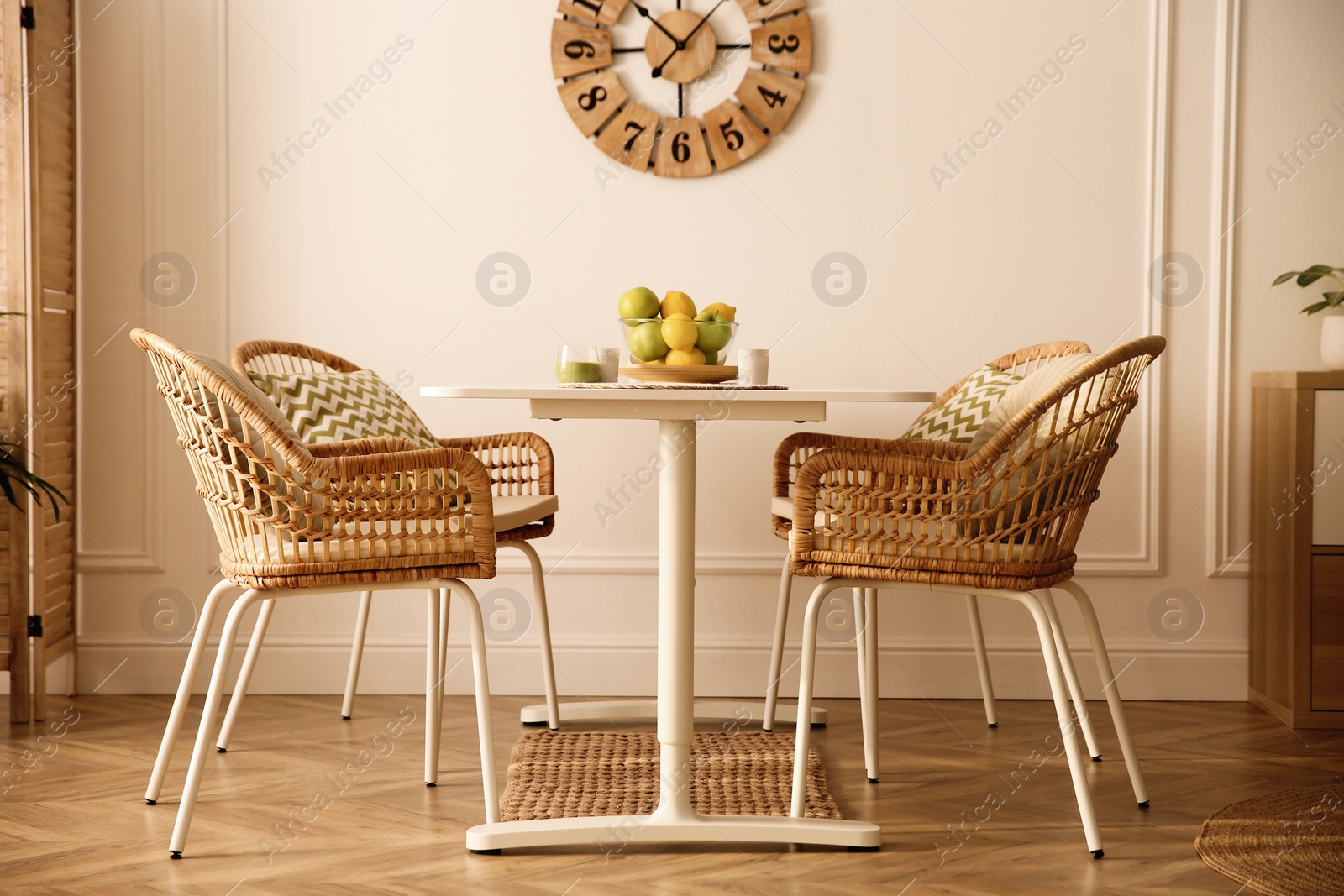 Photo of Stylish white dining table and wicker chairs in room. Interior design