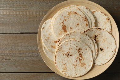Many tasty homemade tortillas on wooden table, top view. Space for text