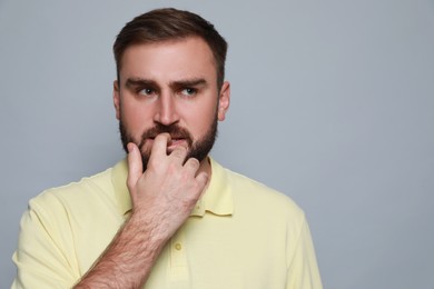 Photo of Man biting his nails on grey background, space for text. Bad habit